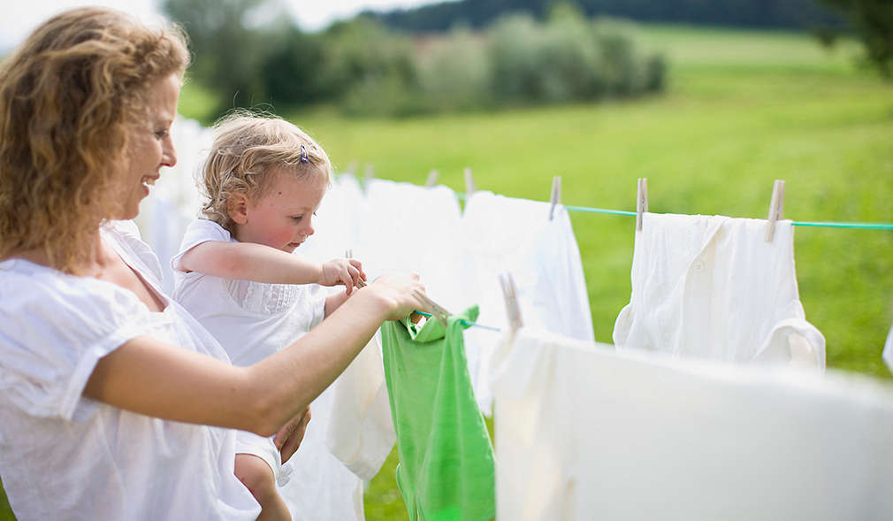 Mama cu copilul ei atârnă rufe pe o sârmă  
