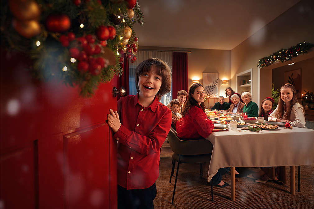 A cozy indoor holiday scene featuring a family gathered around a beautifully decorated dining table, enjoying a festive meal in a warmly lit, Christmas-themed home.