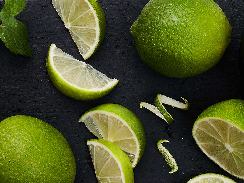 Svježe limete, u komadu i narezane, na crnoj podlozi
