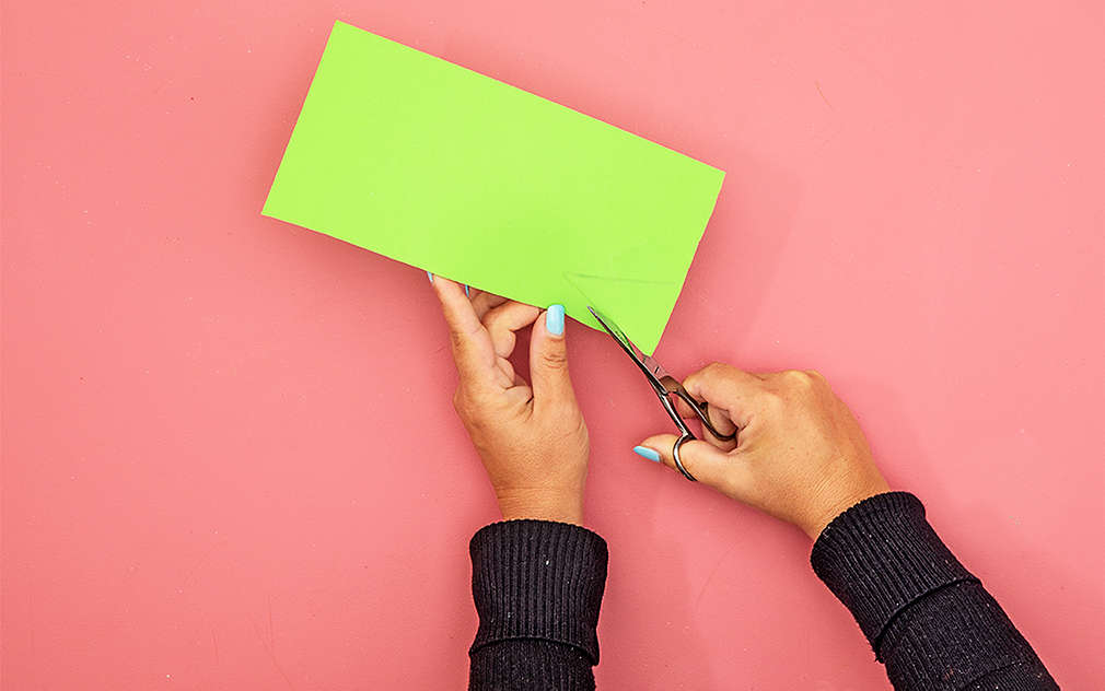 Dve ruky na ružovom podklade niečo vystrihujú zo zelenej penovej gumy.
