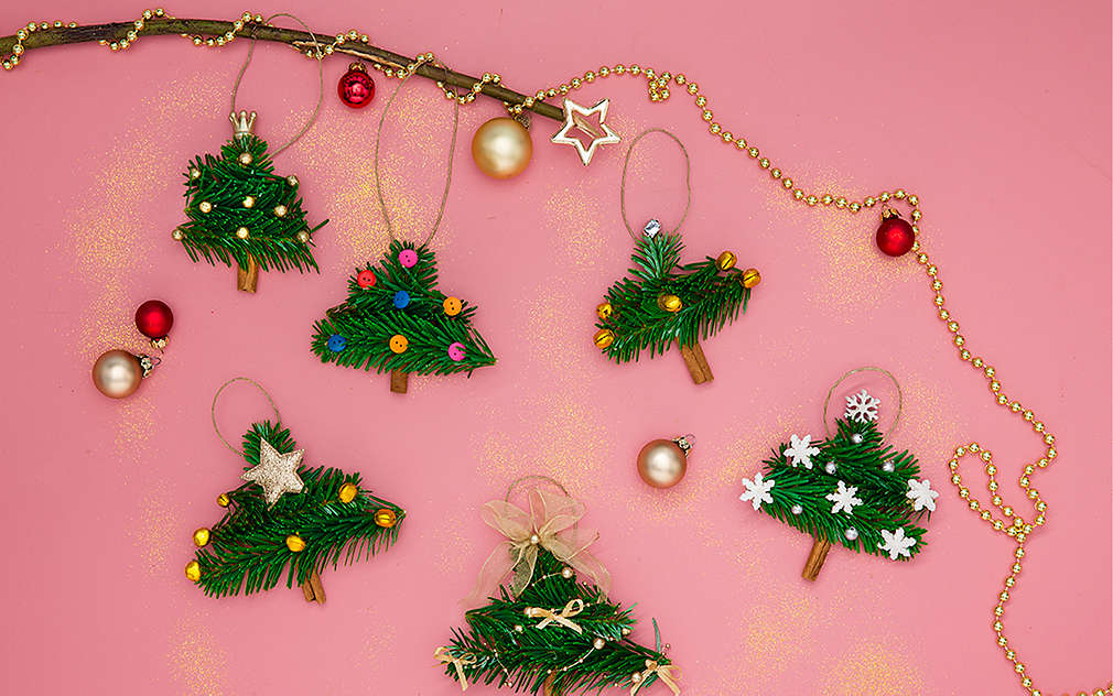 Vianočné stromčeky vyrobené z jedľových vetvičiek sú ozdobne rozložené na ružovom podklade.