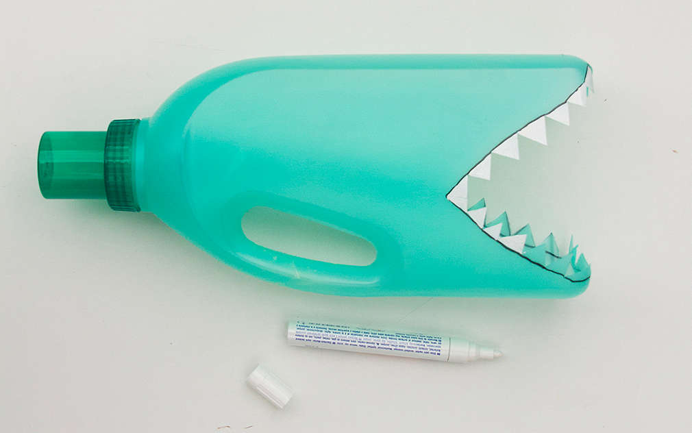 Dinții de pe sticla de plastic verde sunt pictați cu alb.