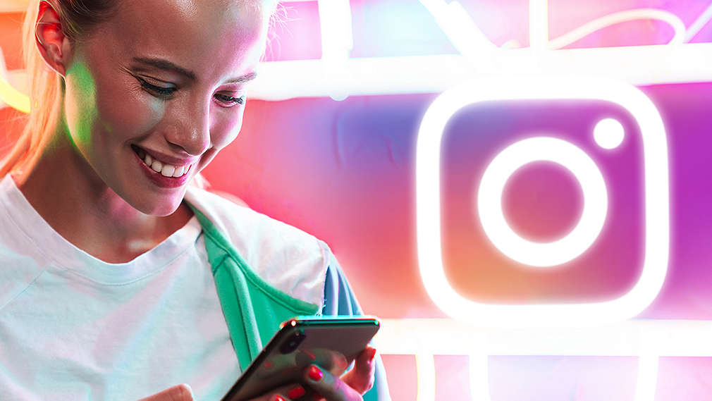 Uśmiechnięta dziewczyna z telefonem w ręce na tle instagramowym.