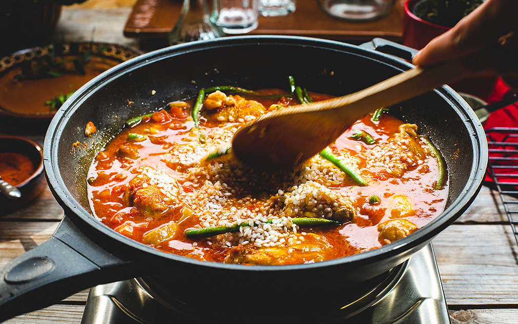 Osoba drži žlicu u tavi s paellom.