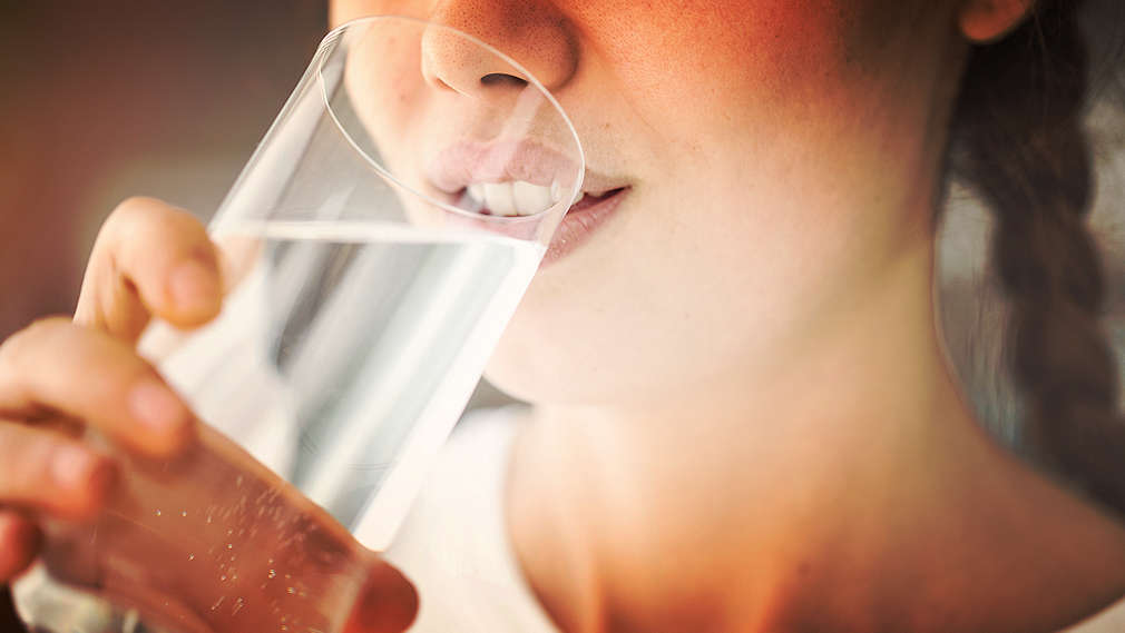 Vedere laterală a feței și a gâtului unei femei care bea apă.