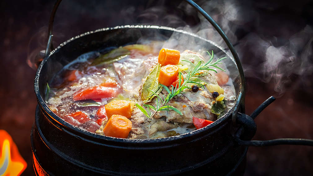 O oală de fontă plină cu legume, fotografiată de sus.