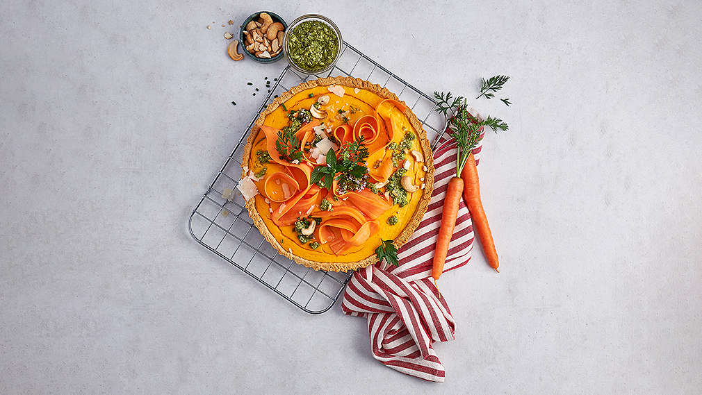 Große, runde Tarte auf einem Rost, danben ein rot-weiß gestreiftes Küchentuch, zwei Möhren sowie zwei weitere kleine Schüsseln. , Gro�e, runde Tarte auf einem Rost, danben ein rot-wei� gestreiftes K�chentuch, zwei M�hren sowie zwei weitere kleine Sch�sseln.