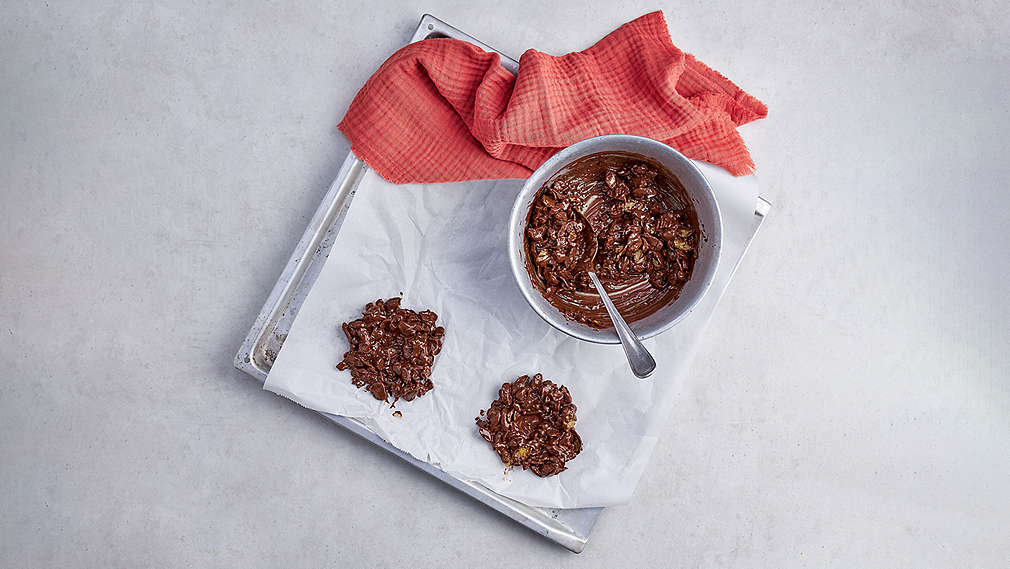Schüssel mit Masse und Löffel auf Blech. Daneben auf dem Blech verteilte Masse in Form von kleinen Nestern., Sch�ssel mit Masse und L�ffel auf Blech. Daneben auf dem Blech verteilte Masse in Form von kleinen Nestern.