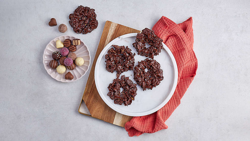 Fertige Nester auf einem Teiller, daneben ein teller mit Pralinen sowie ein rotes Küchentuch. , Fertige Nester auf einem Teiller, daneben ein teller mit Pralinen sowie ein rotes K�chentuch.
