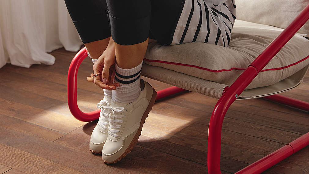 Eine Person sitzt auf einem Sessel und trägt sportliche weiße Esmara Schuhe sowie weiße Tennissocken mit schwarzen Streifen., Eine Person sitzt auf einem Sessel und tr�gt sportliche wei�e Esmara Schuhe sowie wei�e Tennissocken mit schwarzen Streifen.