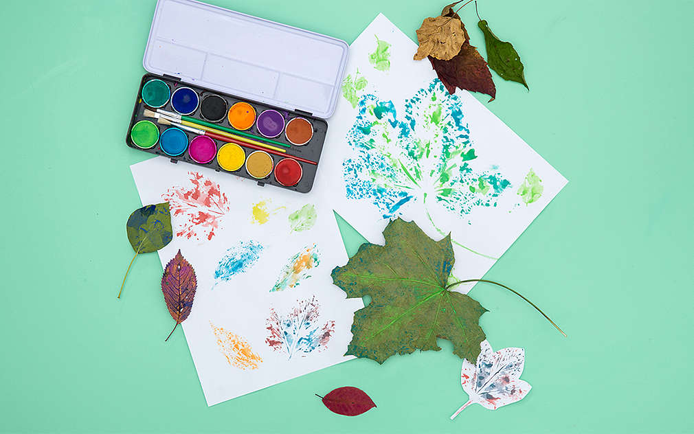 Pohľad zhora na krabičku farieb, listy a opečiatkované papiere.