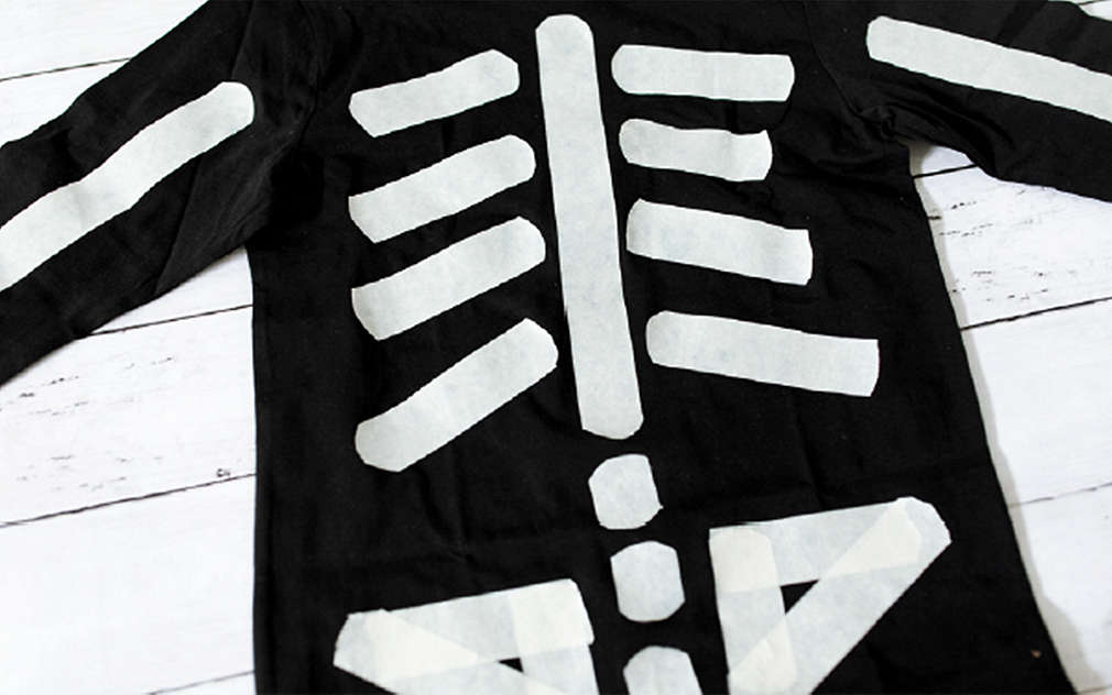 Tričko v podobe kostry je položené na svetlom drevenom podklade.