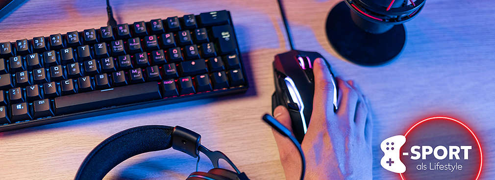 Verschiedene Gaming-Gadgets wie eine Gaming-Tastatur, -Maus sowie ein -Headset liegen auf einem Gaming-Tisch