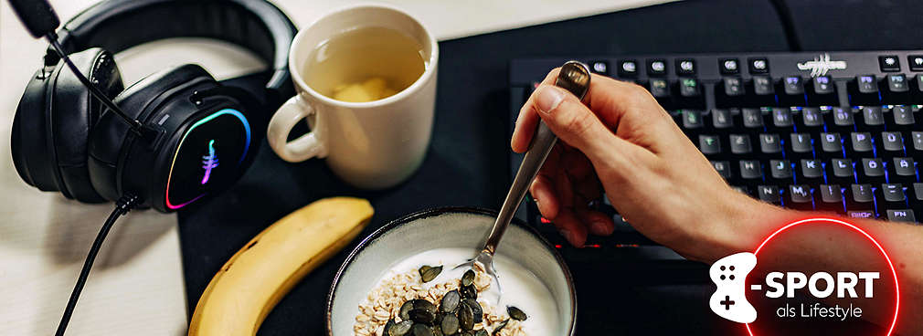 Eine Person im Anschnitt isst Joghurt mit Müsli aus einer Schale, daneben liegt eine Banane, ein Gaming-Headset und eine Gaming-Tastatur