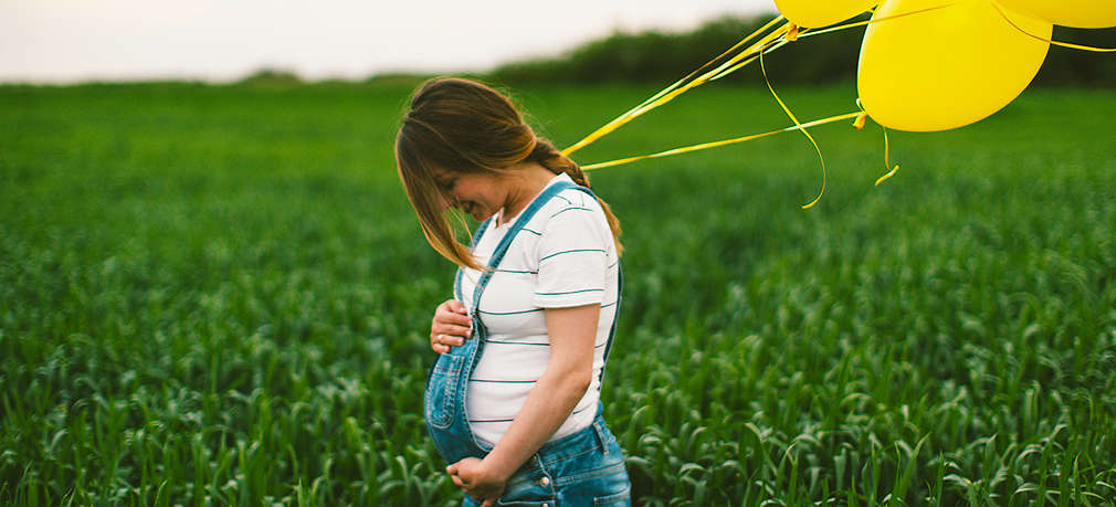 Schwangere Frau posiert mit Luftballons beim Babybauch-Fotoshooting