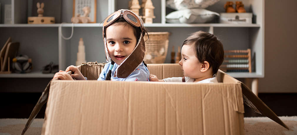 Spielende Kinder sitzen in einem Umzugskarton