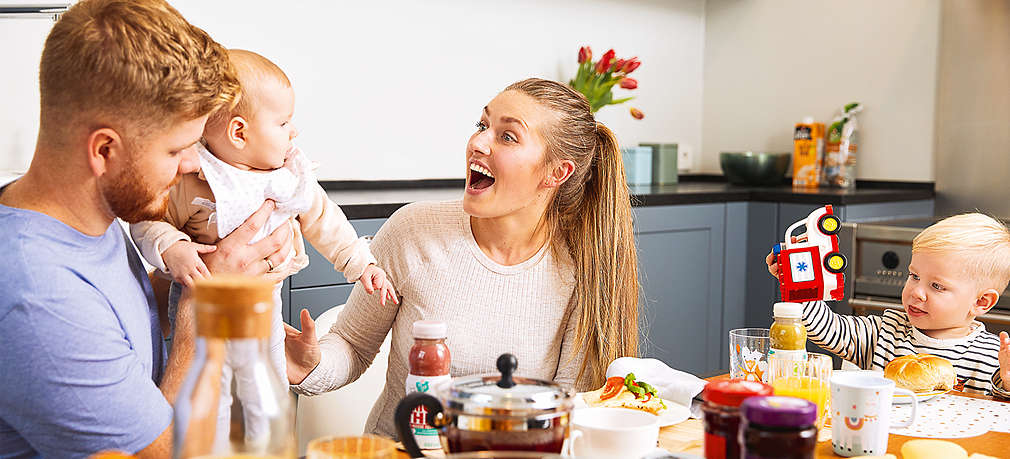 Eltern mit Baby und Kleinkind am Frühstückstisch