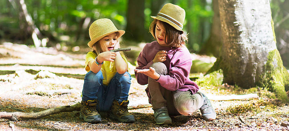 Kinder sitzen auf dem Boden im Wald