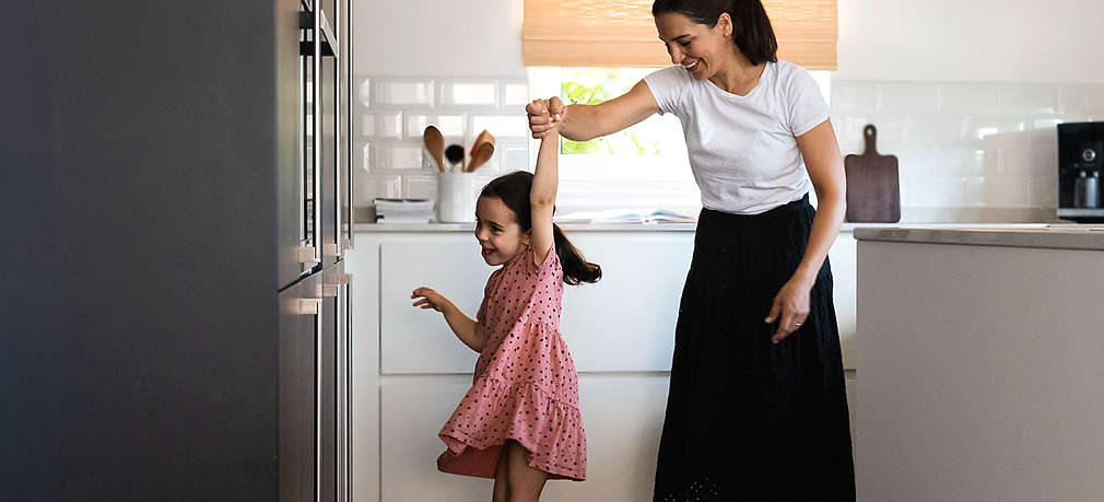 Mutter tanzt mit Tochter in der Küche