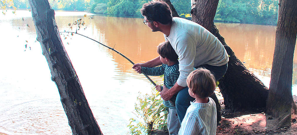 Vater mit Kindern am See