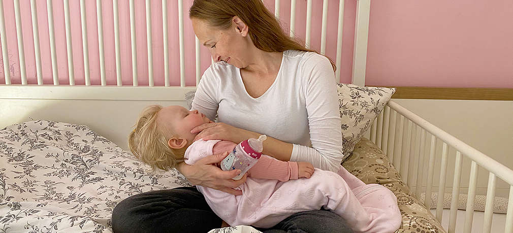 Mutter sitzt mit Baby im Bett