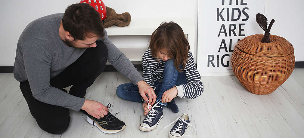 Vater und Kind binden Schuhe