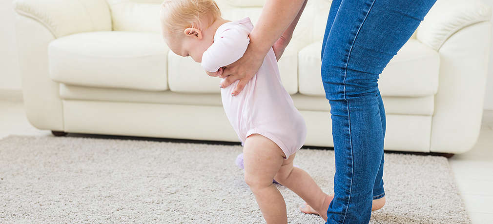 Mädchen läuft mit Hilfe der Mutter