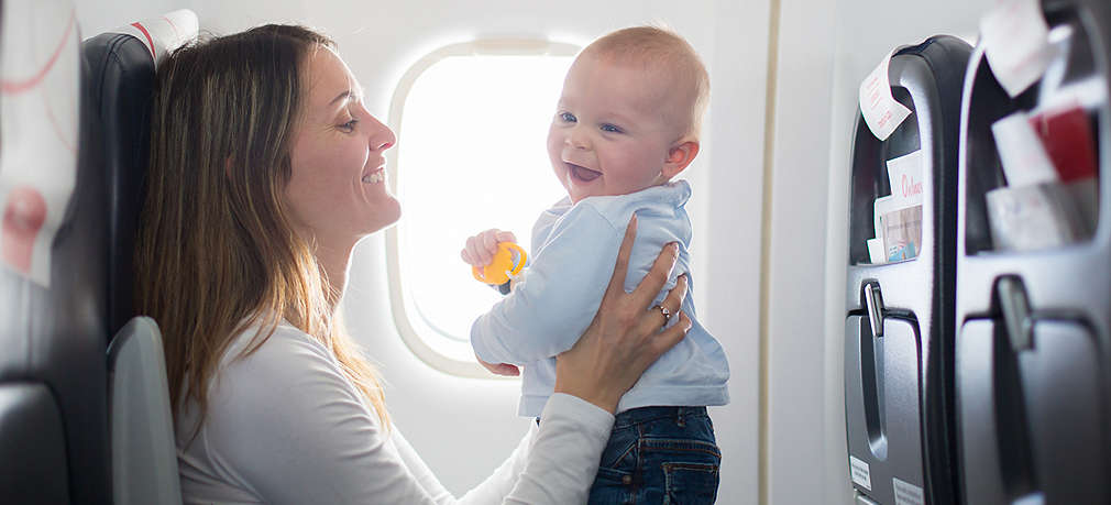 Frau mit Baby in der Hand im Flugzeug