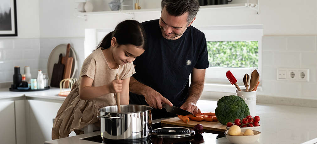 Vater und Tochter kochen gemeinsam am Herd