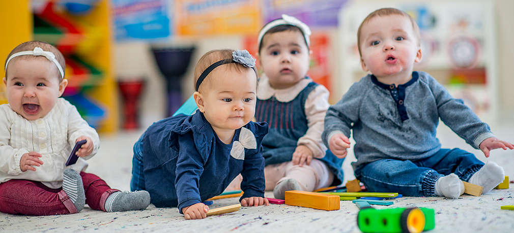 Vier Babys spielen auf dem Boden