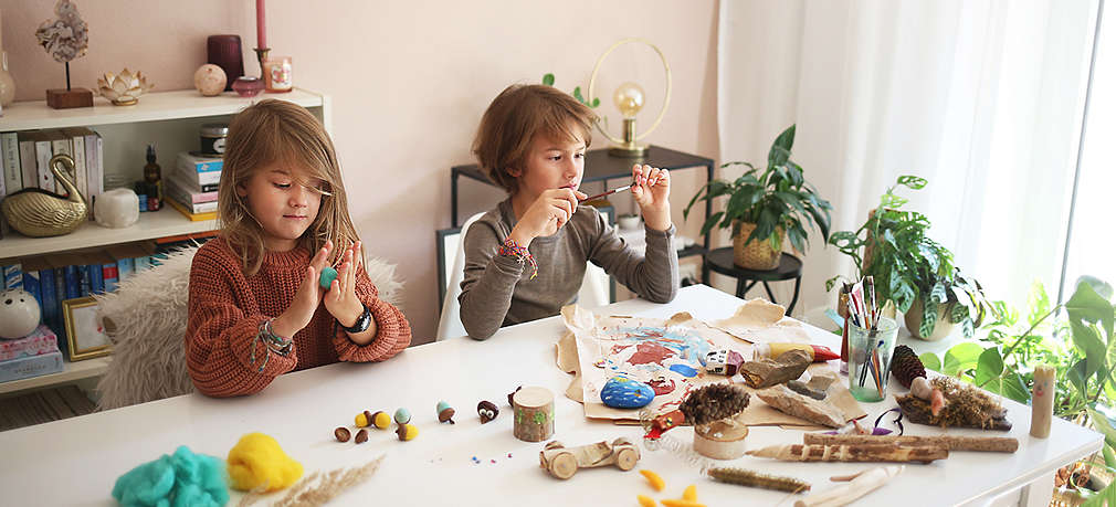 Zwei Kinder sitzen am Tisch und basteln