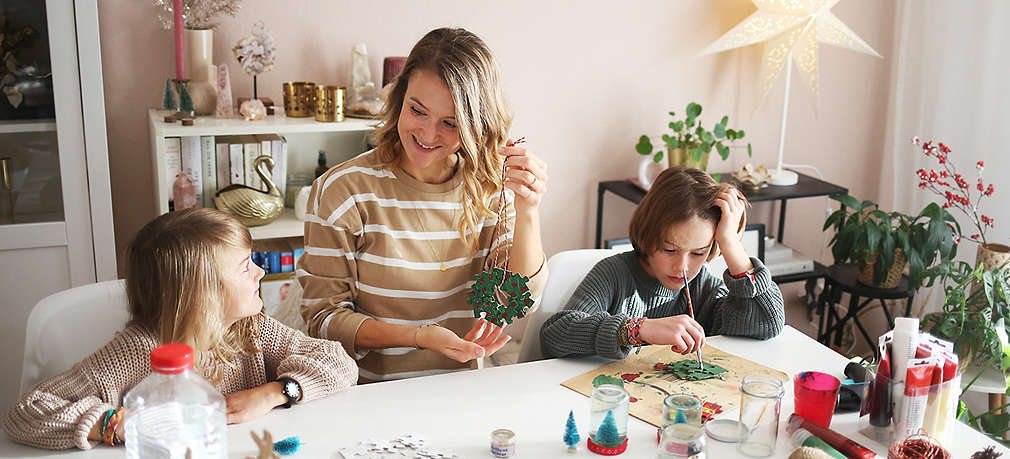 Mutter bastelt mit ihren zwei Kindern Weihnachtsgeschenke