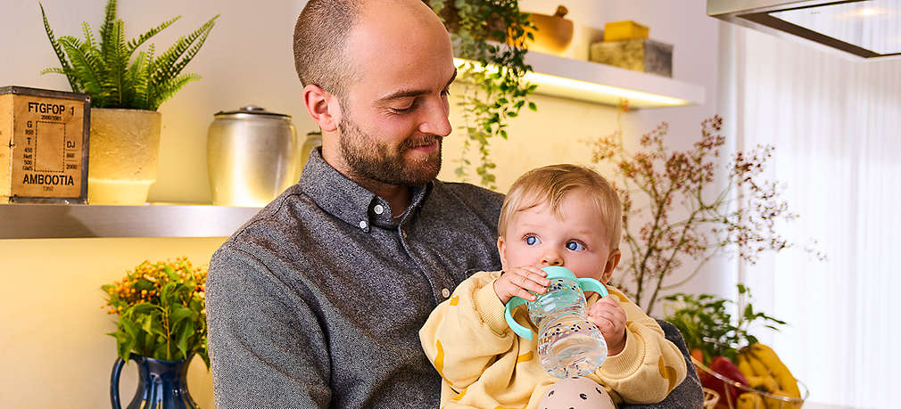 Vater mit trinkendem Kind auf dem Arm