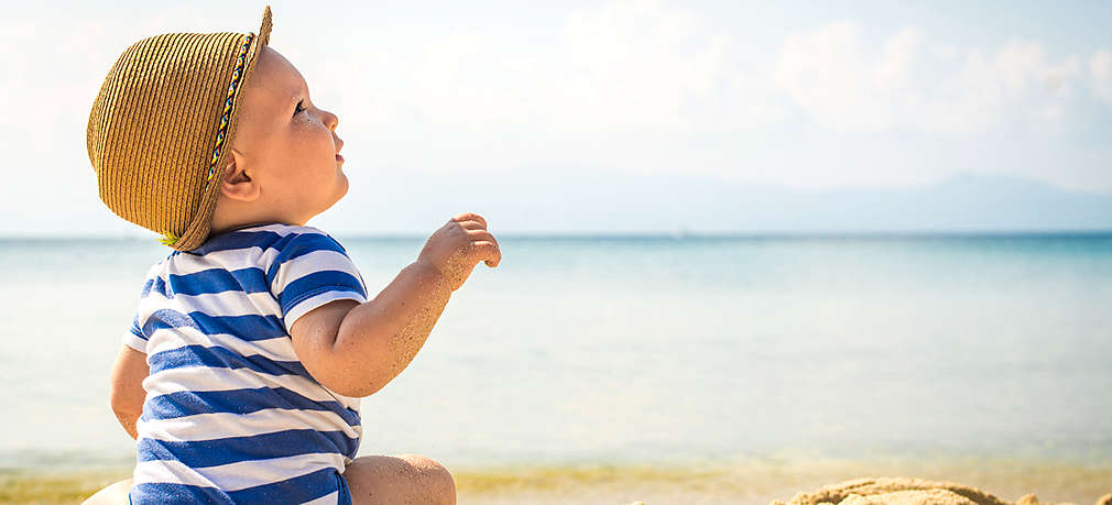 Baby sitzt am Strand