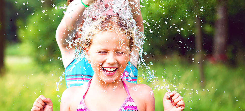 Kinder spielen im Sommer mit Wasser