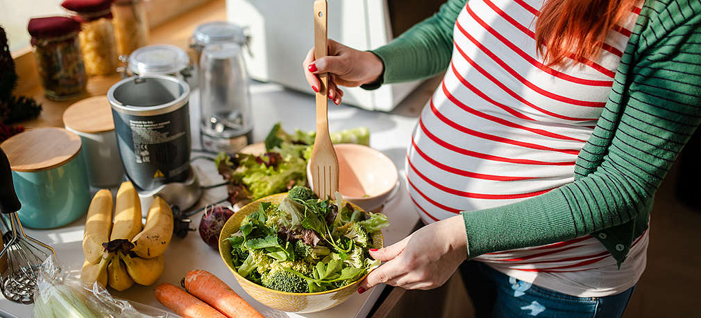 Schwangere bereitet sich einen Salat zu