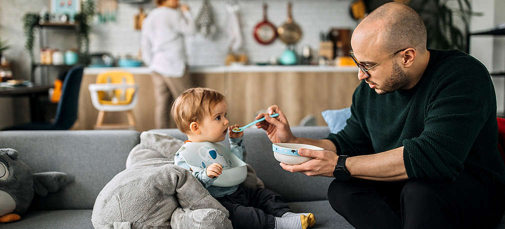 Vater füttert Kind mit Brei