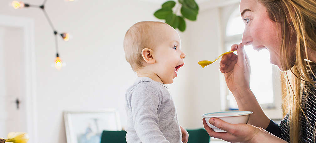 Mutter füttert Baby mit Brei