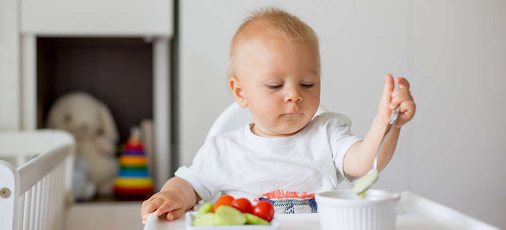 Baby sitzt im Hochstuhl vor seiner Mahlzeit