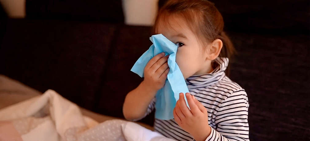 Krankes Kind putzt sich die Nase