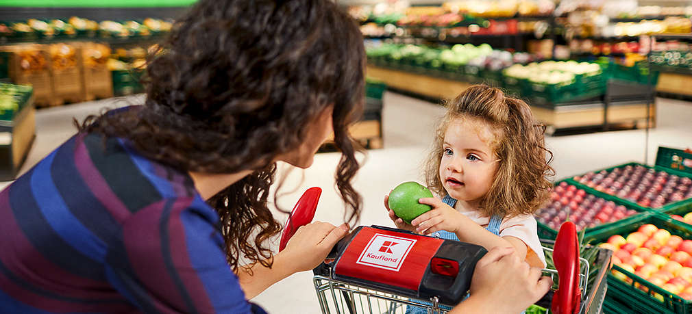 Mutter fährt ihre Tochter im Einkaufswagen im Supermarkt