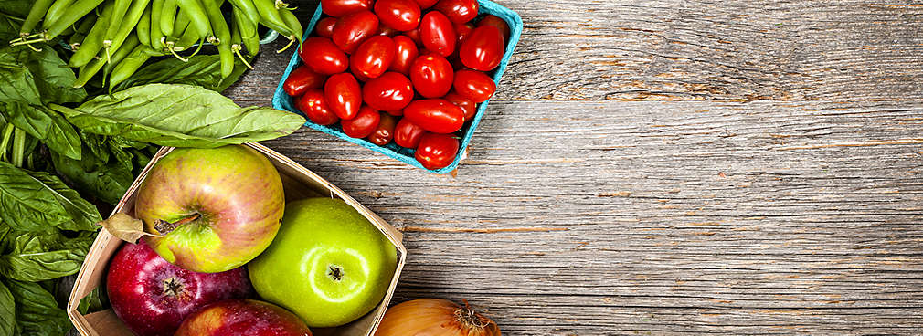 Frisches Obst und Gemüse liegt auf einem Holztisch