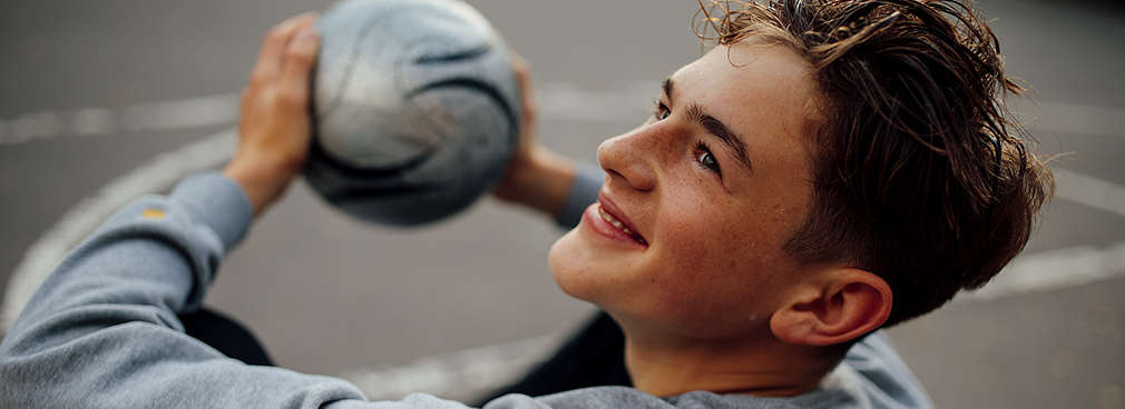 Lächelnder Junger auf einem Sportfeld denkt über seine berufliche Zukunft nach