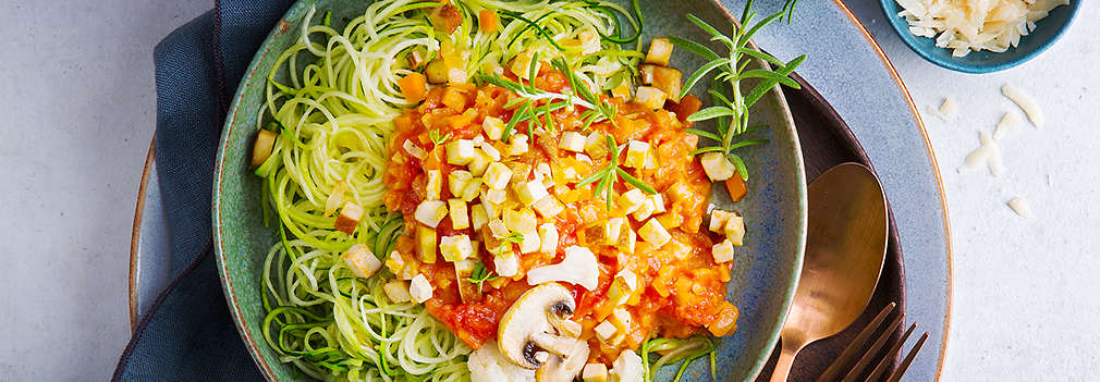 Ein von oben fotografierter Teller mit Zoodles und verschiedenen Gemüsesorten sowie Tofu