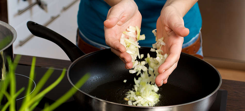 Fein geschnittene Zwiebeln werden in eine Pfanne zum Anschwitzen gegeben