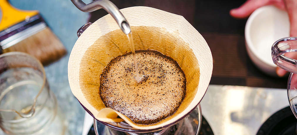 Gemahlener Kaffe wird in einem HAndsieb mit heißem Wasser aufgegossen