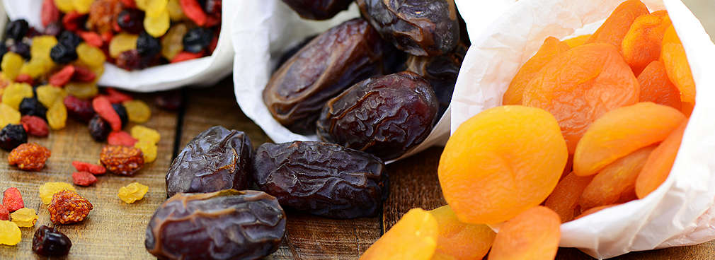 Gedörrtes Obst liegt in weißen Tütchen auf einem Holztisch