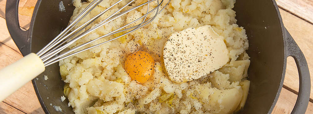 Ein Eigelb, Butter und Gewürze werden in Kartoffelbrei gerührt