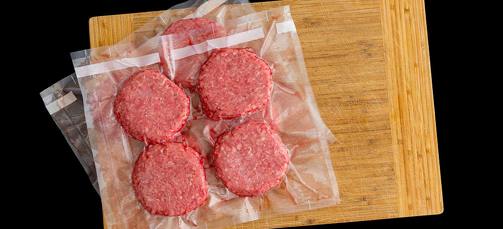 Vakuumiertes tiefgefrorenes Hackfleisch liegt auf einem Schneidebrettchen