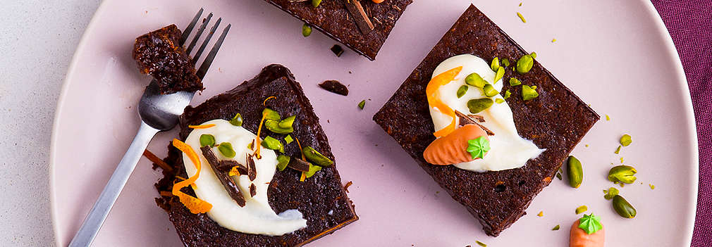 Vier Brownies mit Topping und einer Gabel auf einem rosafarbenen Teller